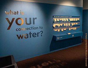 Wand in der Ausstellung "Our Connection to Water" mit der Frage "What is your connection to water?" und mehreren Notizzetteln, die Antwort auf diese Frage geben.