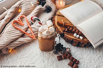 Gemütliches Ambiente in der Zeit nach Weihnachten mit Kakao, Schokolade und einem Buch.