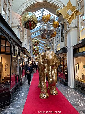 Auf dem roten Teppich in der Burlington Arcade steht ein goldfarbener lebensgroßer Elefant.