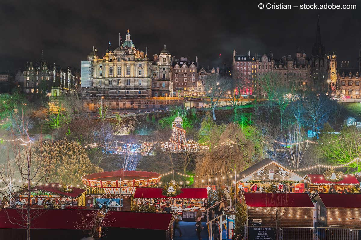 Die Altstadt von Edinburgh und der hell erleuchtete Weihnachtsmarkt am Abend.