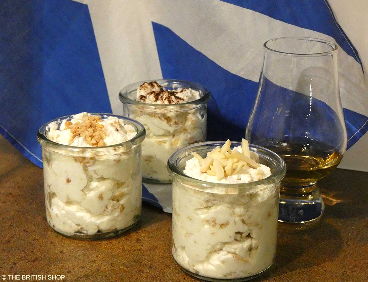 Drei mit Edinburgh Fog gefüllte Dessert-Gläser und ein Whisky-Glas vor der schottischen Fahne